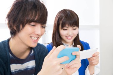 Genç çift cep telefonu kullanıyor, oyun oynuyor. 