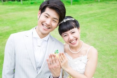 Gelin ve damat parkta yüzükler gösteriyor.