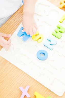 Masada renkli köpük harfleri düzenleyen çocuk