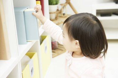 Asyalı çocuk kitaptan kitap seçiyor.