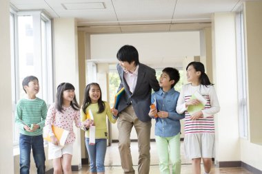 Öğretmenli bir grup Japon çocuk okul koridorunda yürüyor. 