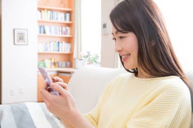 Evde cep telefonu kullanan bir kadın 