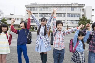 Okul bahçesinde el ele tutuşan bir grup Japon çocuk. 