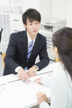 Genç Asyalı işadamı kadın müşteriyle birlikte çalışıyor.