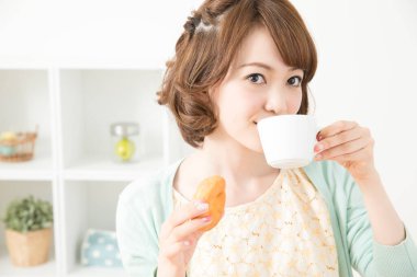 Asyalı genç ev hanımı kahvaltı yapıyor.