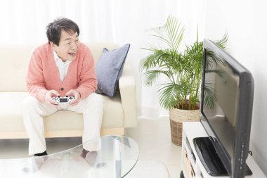 Son sınıf öğrencisi kanepede oturuyor ve evde video oyunu oynuyor.