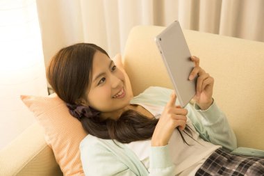 Tablet bilgisayar kullanan Asyalı genç bir kadın..