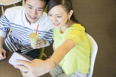 Asyalı çift kahve molasında selfie çekiyor. 