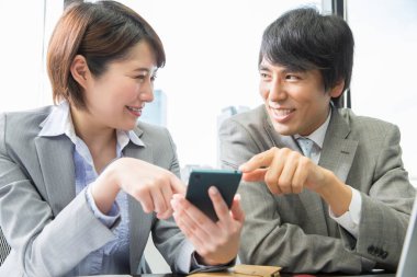 Ofisinde akıllı telefonu olan bir iş kadını.