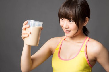 Genç sağlıklı Asyalı kız milkshake içiyor.