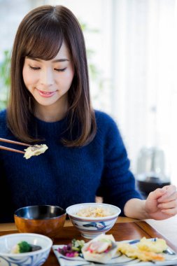 Asyalı kadın yemek çubuğu yiyor.