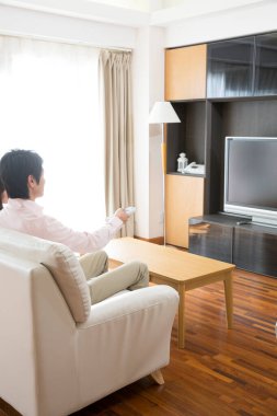 Genç Asyalı çift evde televizyon izliyor.