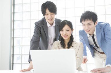 Genç Japon iş adamları ofiste dizüstü bilgisayarla çalışıyorlar.