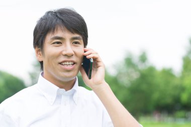 Genç Asyalı adam cep telefonundan konuşuyor.