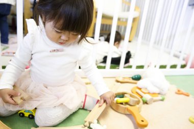 Küçük sevimli Asyalı kız oyuncaklarla oynuyor.