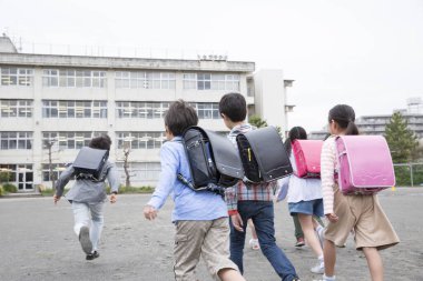 Asyalı bir grup öğrenci okulda yürüyor. 