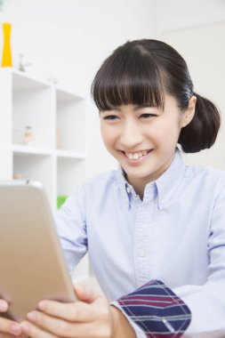 Tablet bilgisayar kullanan gülümseyen Çinli kız.