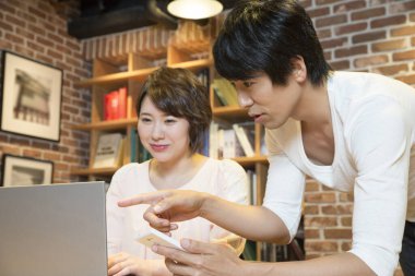 Ofiste bilgisayarla çalışan Asyalı genç kadın ve erkek.