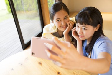 Mutlu Asyalı kızlar evde selfie çekiyor.