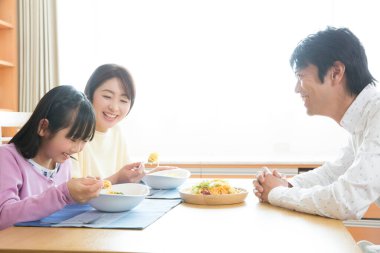 Sabahları kahvaltı eden üç kişilik mutlu bir aile.