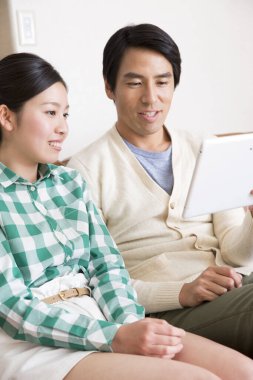 Tablet bilgisayar kullanan Asyalı genç adam ve kadın