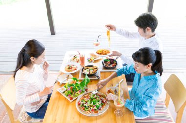 Genç Asyalı arkadaşlar kafede öğle yemeği yiyorlar.