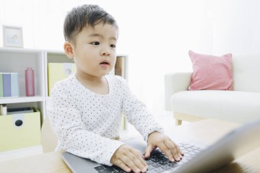Asyalı çocuk evde dizüstü bilgisayarla oynuyor