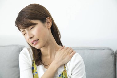 Evde omuz ağrısı çeken bir kadın.