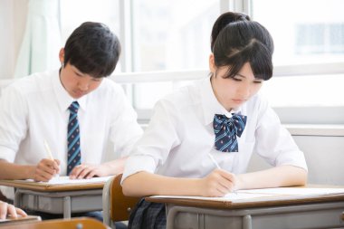 Asyalı öğrenciler sıralarda çalışıyor.