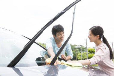 Gülümseyen Japon çift sokakta araba yıkıyor.