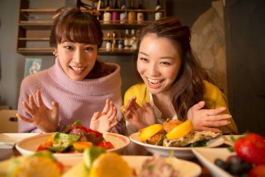 Mutlu Asyalı kadın arkadaşlar kahvaltının tadını çıkarıyorlar.