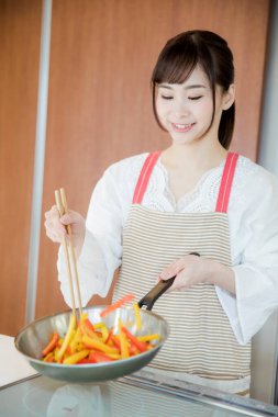 Genç Japon kadının portresi mutfakta yemek hazırlıyor. 