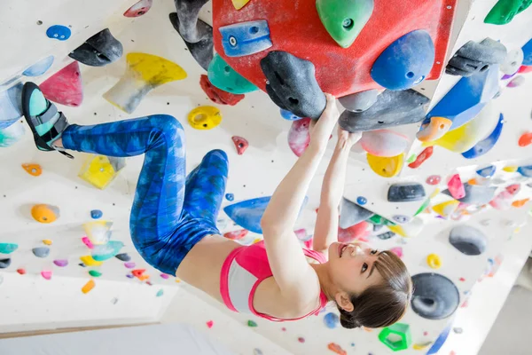 Sportif Asyalı kadın kaya duvarına tırmanıyor