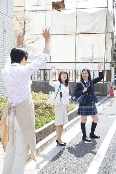 Asyalı bir adam karısına ve kızına veda ediyor.