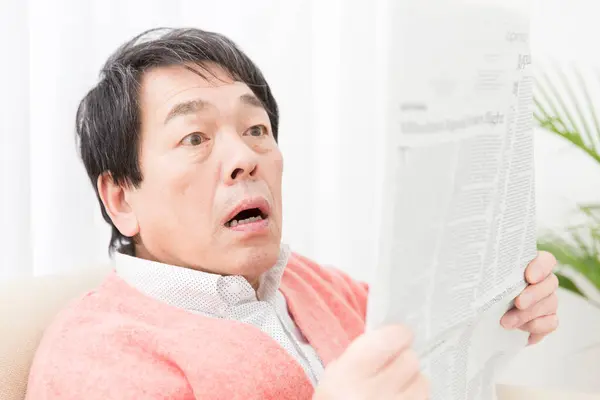 asian man reading news in newspaper