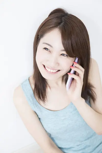 スマートフォンで笑顔で話す若い女性 — ストック写真