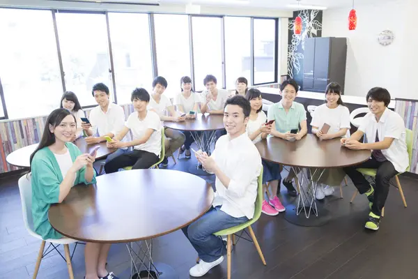 Genç Asyalı öğrenciler sınıfta akıllı telefon kullanıyorlar.