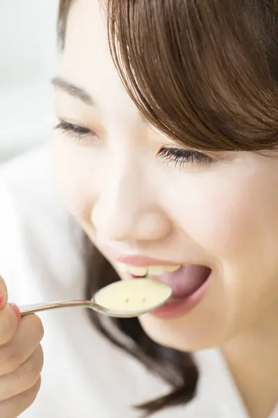 年轻的亚洲女人在用勺子喝汤 — 图库照片