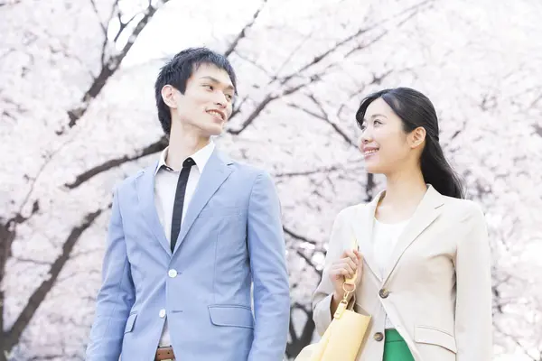 Parkta çiçek açan sakura ağaçları olan genç Asyalı çift.