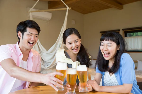 Smiling Asian friends drinking beer at hotel room during vacation