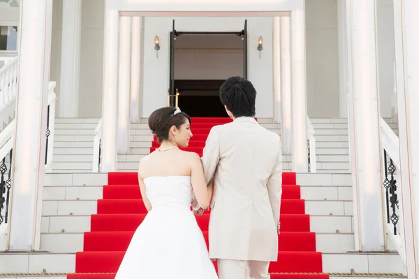 美丽的年轻夫妇穿着红地毯走在楼梯上的倒影 — 图库照片