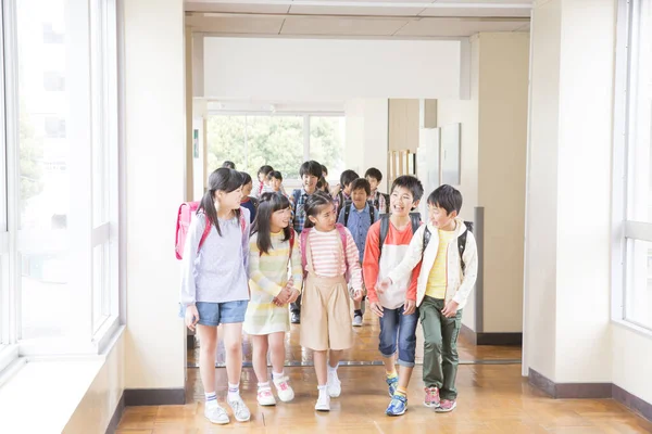 Grupa Japońskich Dzieci Plecakami Spacerujących Korytarzu Szkolnym — Zdjęcie stockowe