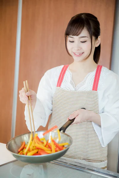 Genç Japon kadının portresi mutfakta yemek hazırlıyor. 