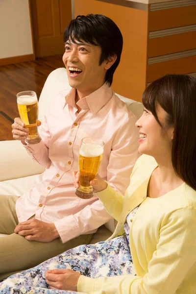 young asian couple drinking beer at home at living room