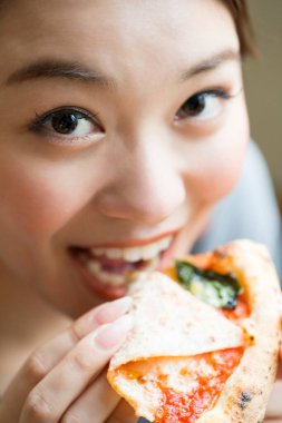 Kafede pizza yiyen Asyalı kadın.