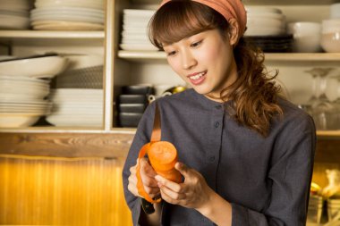 Asyalı genç bayan garson mutfakta havuç soyuyordu.