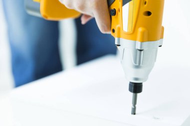 Kadın delmek için elektrikli matkap kullanıyor.  