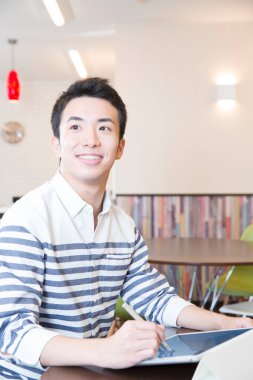 Genç Asyalı adam çizim için dijital tablet kullanıyor 