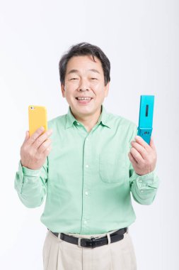 Beyaz arka planda duran akıllı telefonu ve cep telefonu olan Asyalı işadamı..