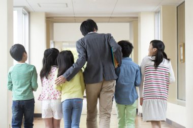 Okulda öğretmenlerinin yanında duran bir grup çocuk. 